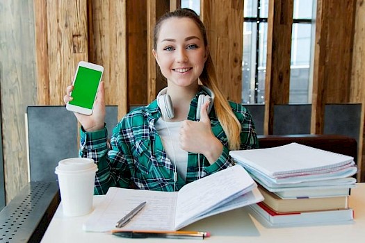 young girl studying at desk with iphone on lockdown