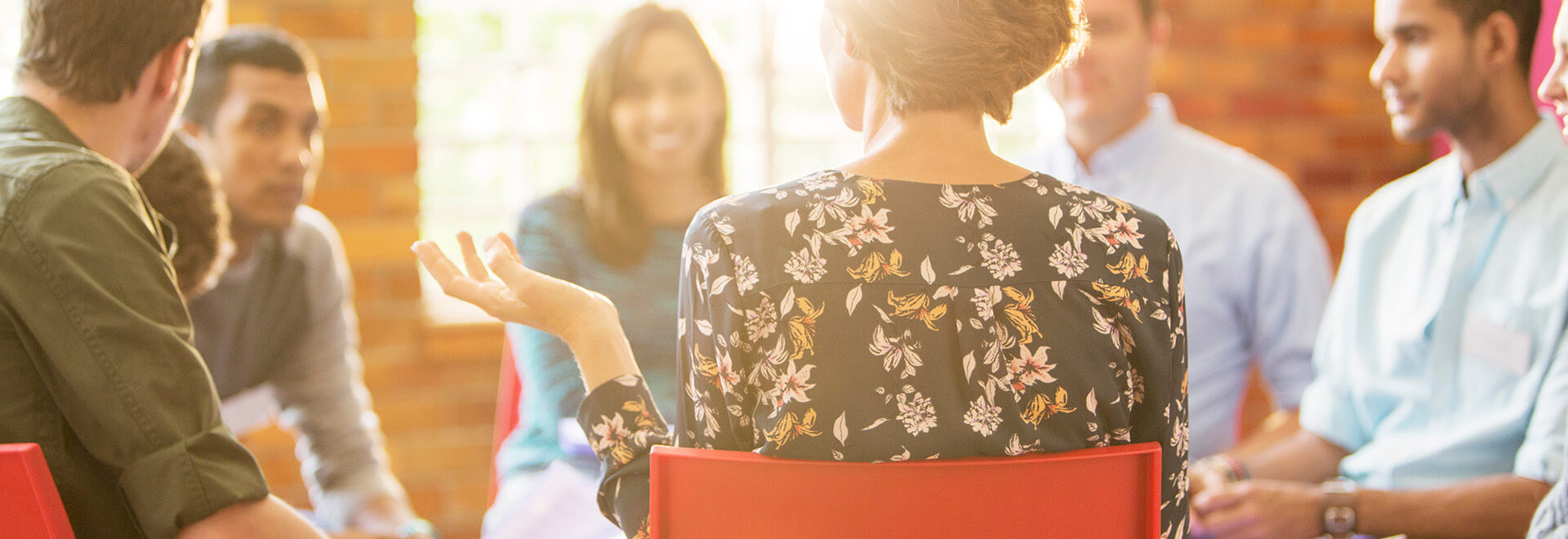 A group of people sitting in a sunlit circle for a workshop or support group discussion.