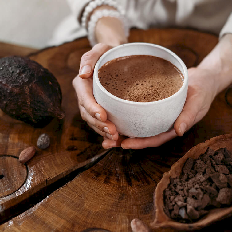 Close-up of a frothy chocolate drink in a ceramic mug held by a person