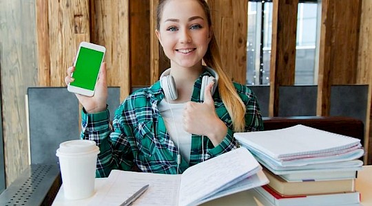 young girl studying at desk with iphone on lockdown